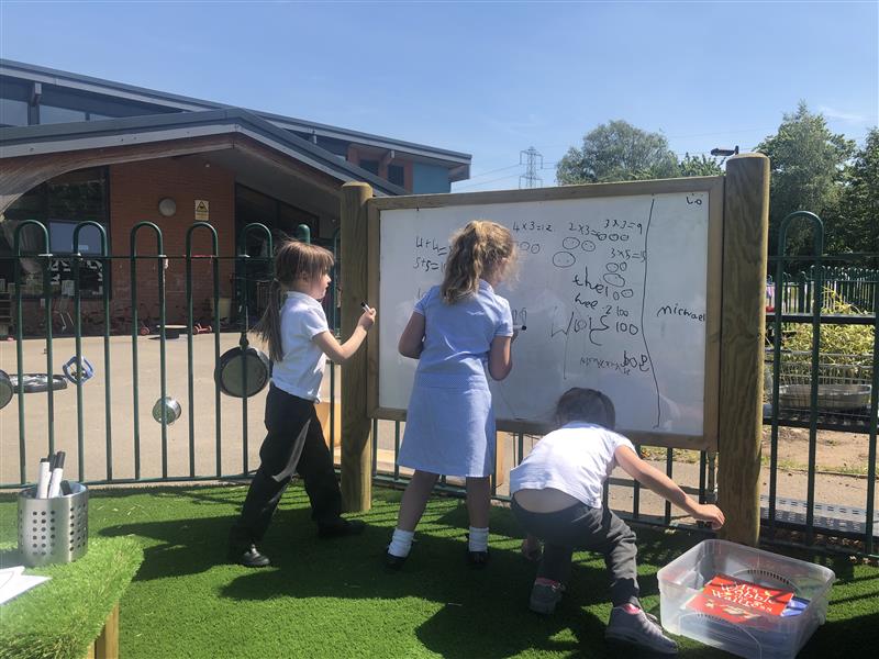 children stand and write letters on the giant whiteboard