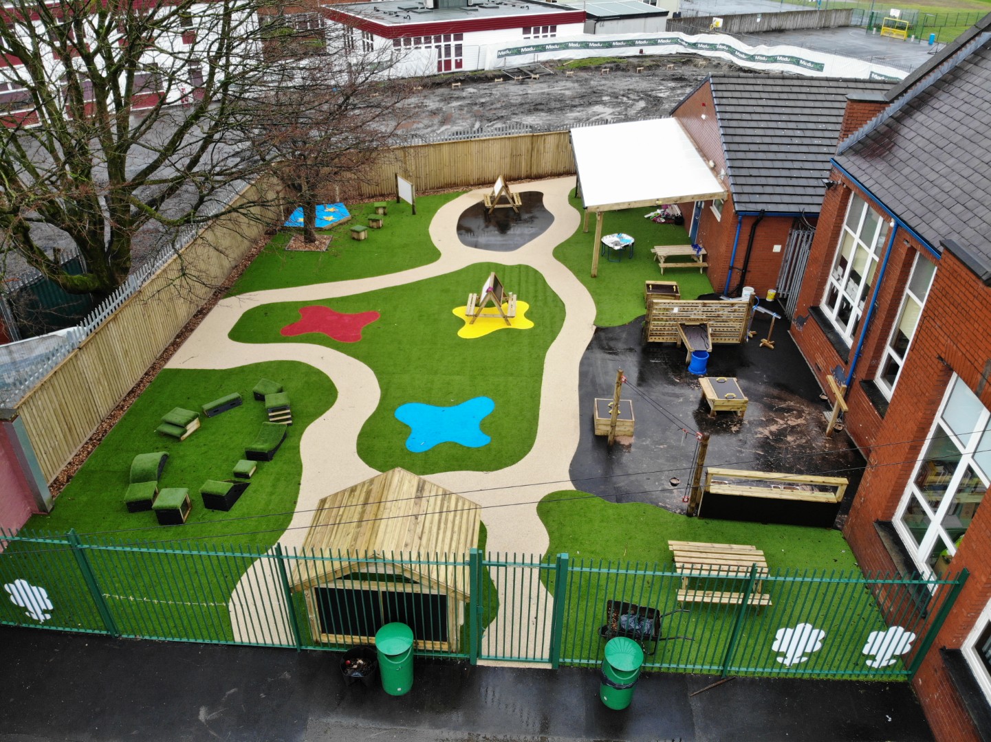 An artificial grass playground with a wetpour path featuring freestanding playground equipment.