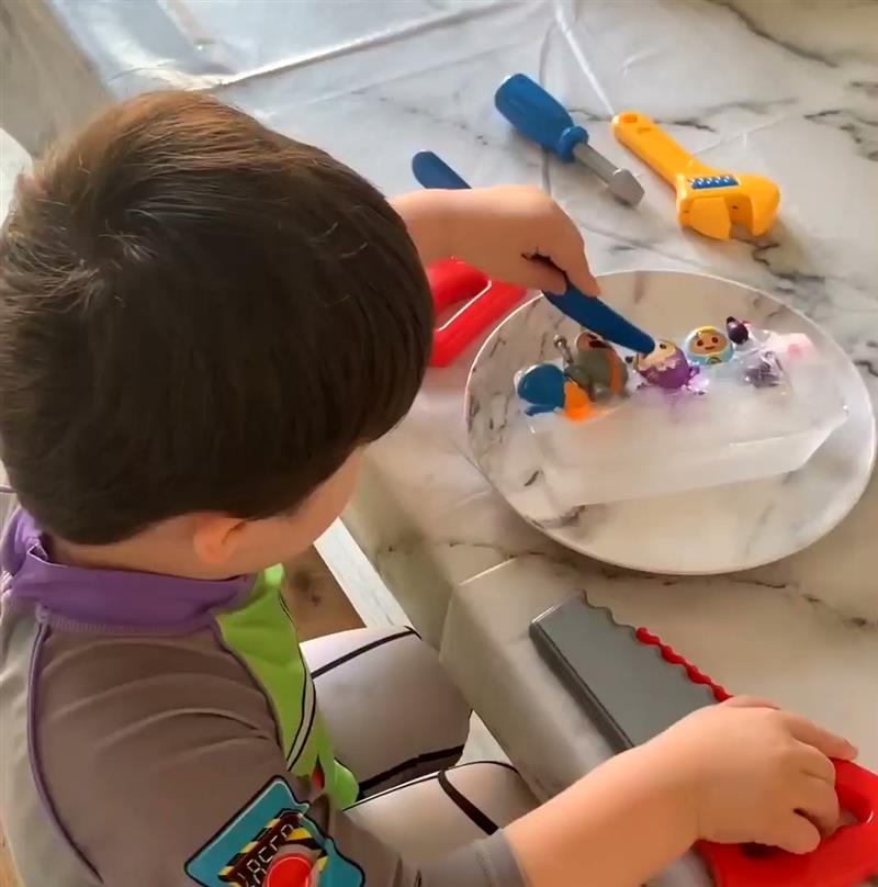 a little boy sits at his table and mixes and makes craft items