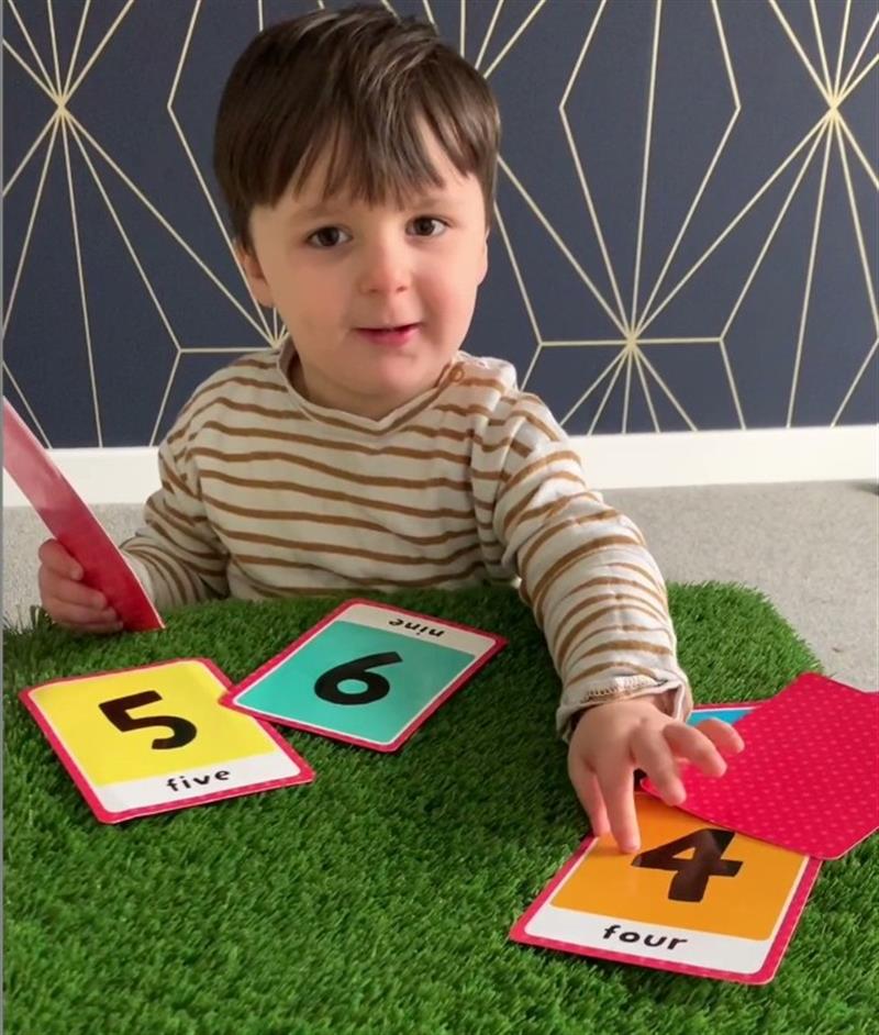 a child sits with number cards in front of him 
