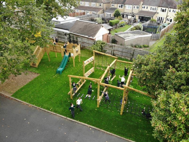 A birds eye view of children playing on their new playground, artificial grass surround the climbing equipment