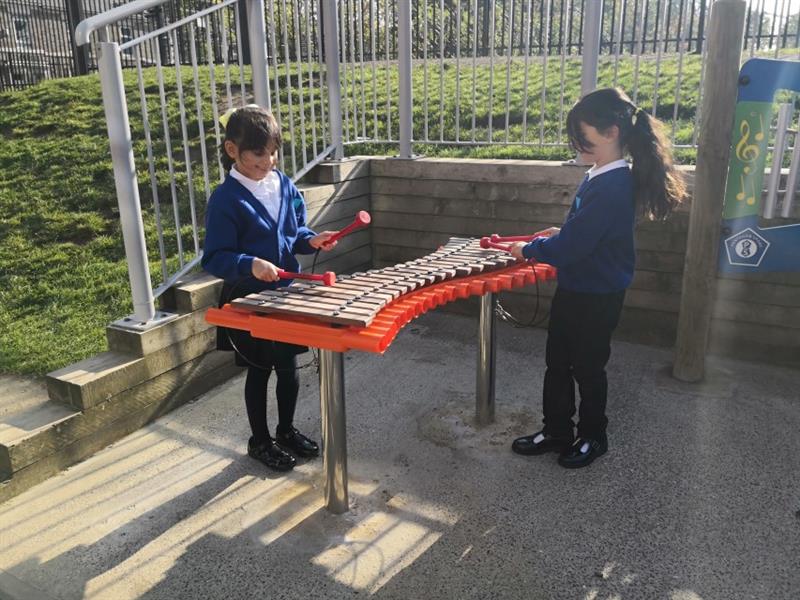 2 young girls playing on a xylophone