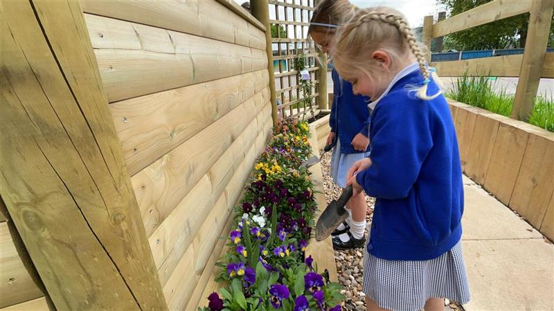 a child interacts with nature by digging in the planters