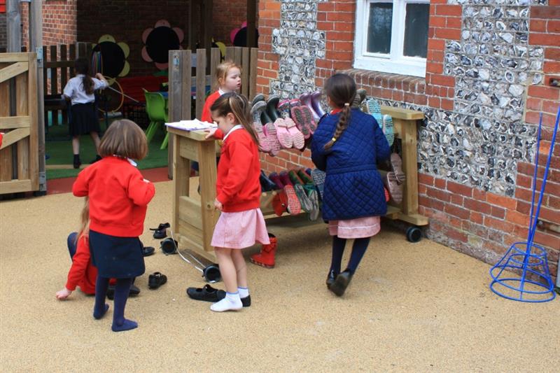 a group of children store their wellies on the welly rack outdoors