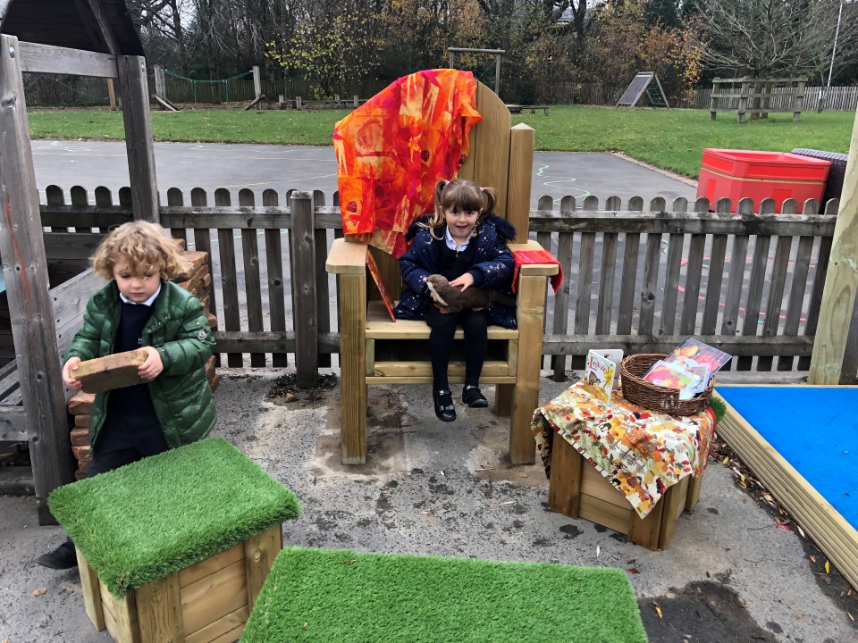 Two children are sat on freestanding seating options as they look to the camera and smile.