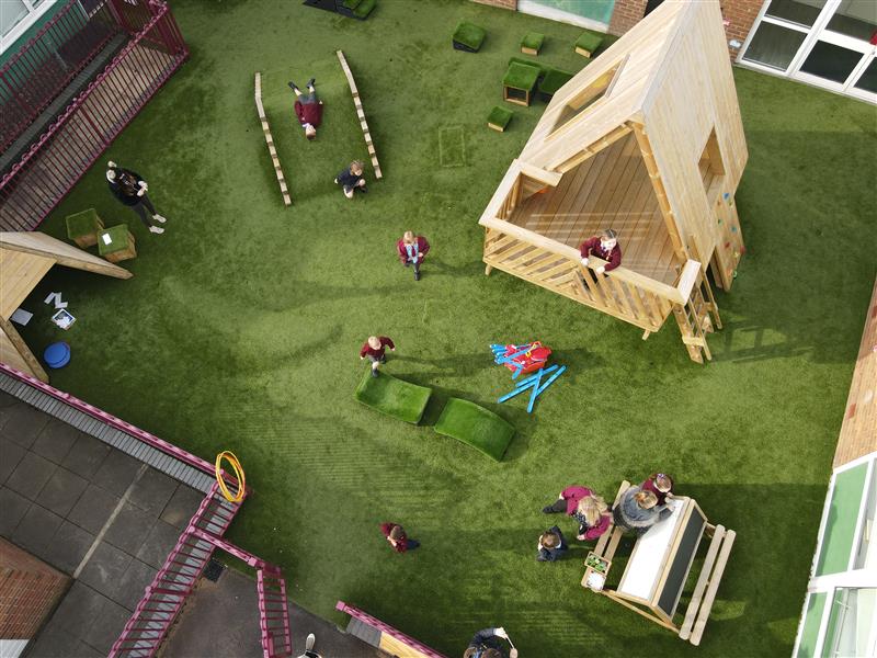 a birdseye shot of the geren artiical grass with the treetop learning den and a wigwam and climb through tunnel hill