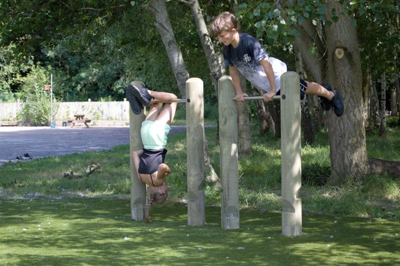 two children in non-school uniform use the roll over bars to flip over