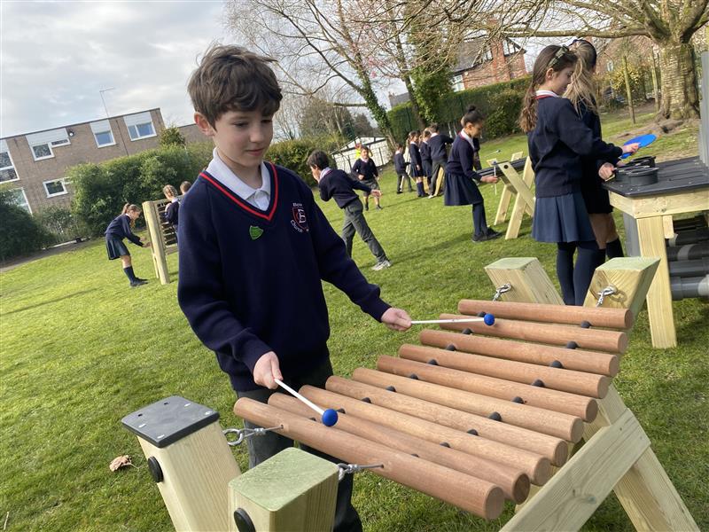 a child stands at the marimba and hits it with the plastic paddle