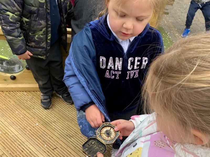a child stands showing off the compass that they have found during a treasure hunt