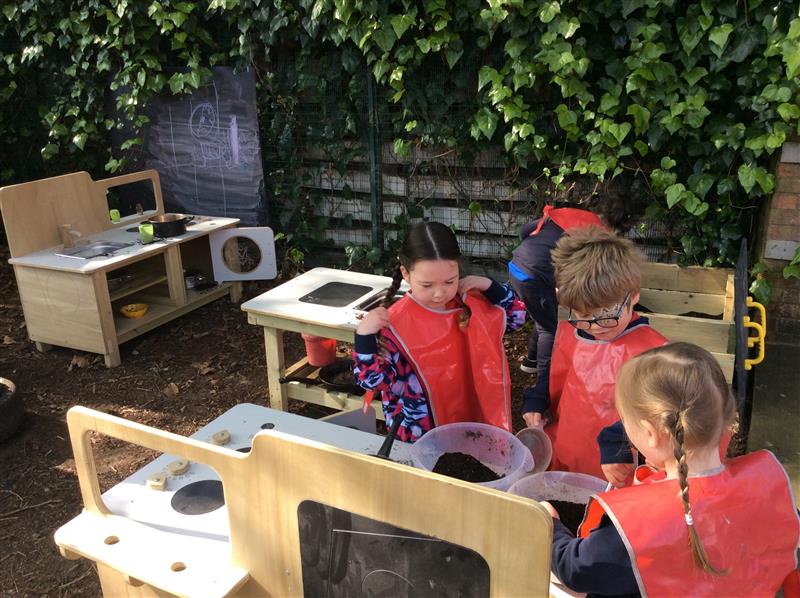 children play with the mud kitchen and a bowl of mud