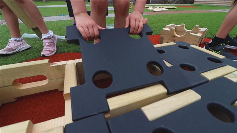 A close up picture of a child slotting the tile on top of the construction block 