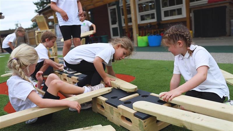 A group of young girls putting the planks into the construction blocks 