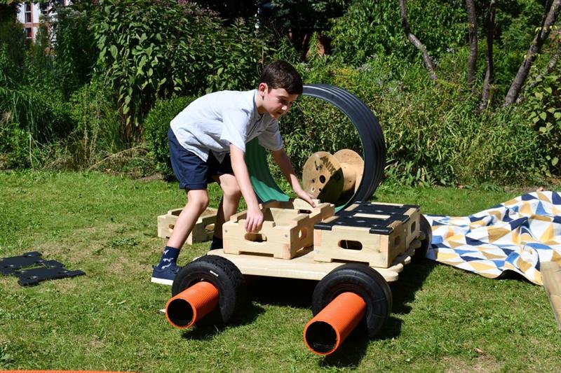 a child makes a moveable car using loose scrap parts and the new pentagon play builder