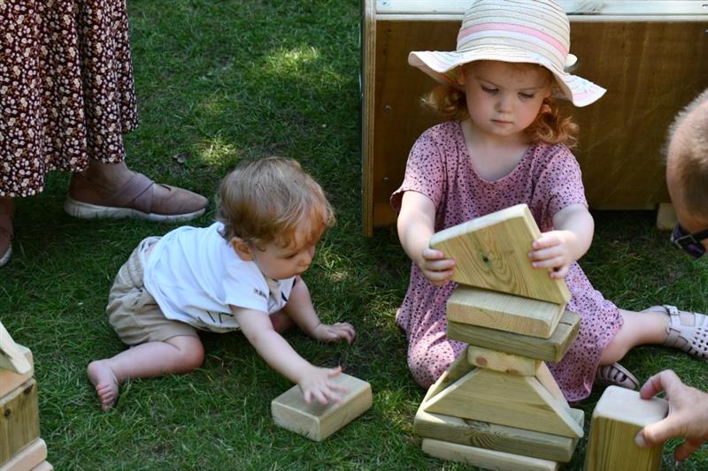 two children sit on the floor and stack blocks