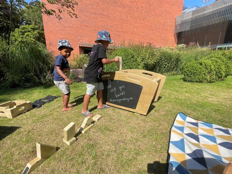 children run around barefoot on the grass and build with the blocks on the grass