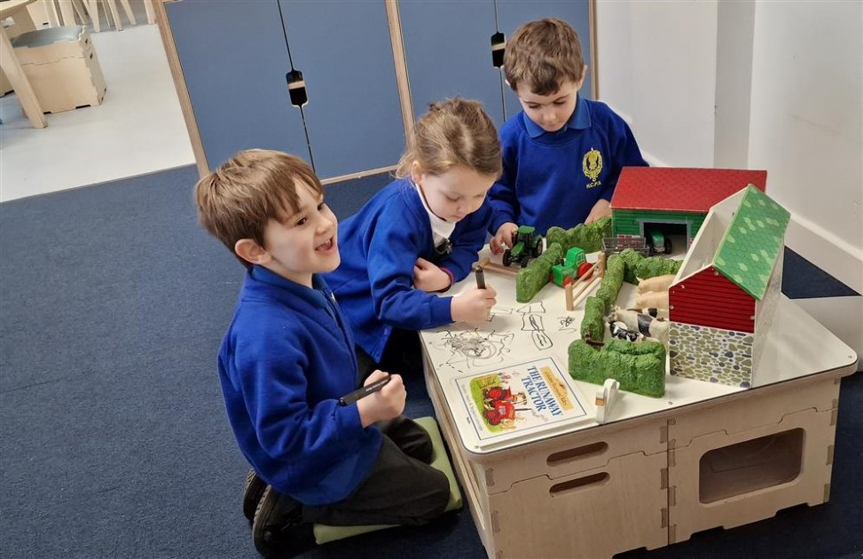 Three children are carrying out an activity on a table. The children look engrossed and happy with the activity.