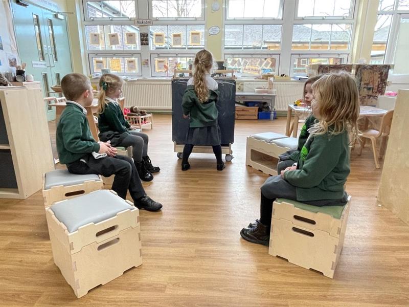 children sit on the stools and benches included in the stack and sit packages, whilst a child stands and draws on the low-level easel