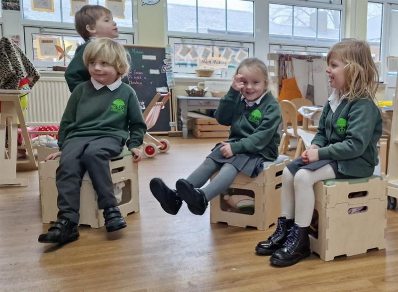 children sit on the stools and smile at the camera