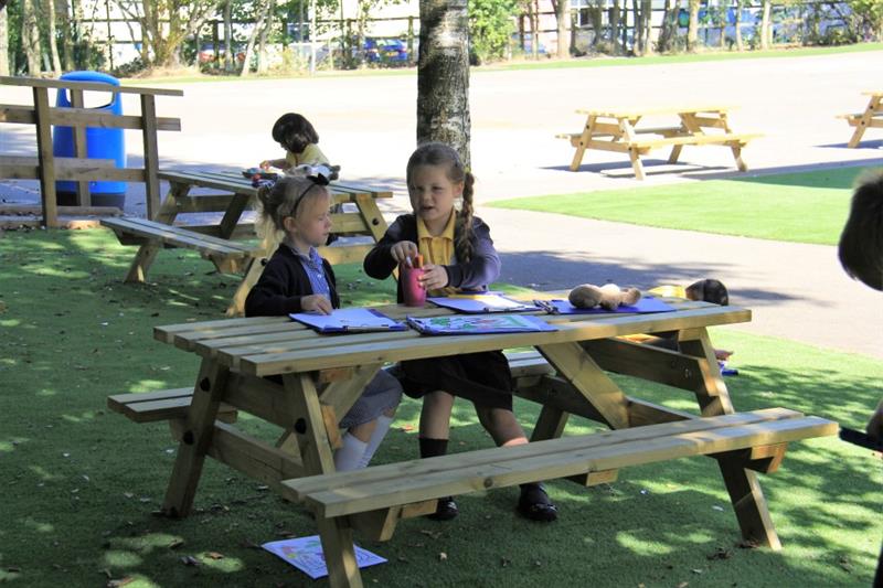 two little girls sit at a picnic table and have some lunch