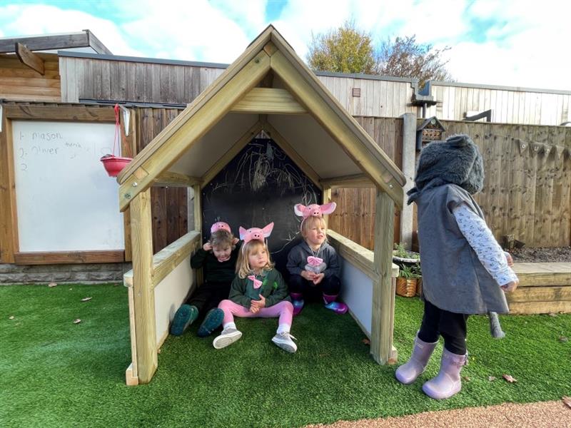 children sit and play 3 little pigs inside the playhouse