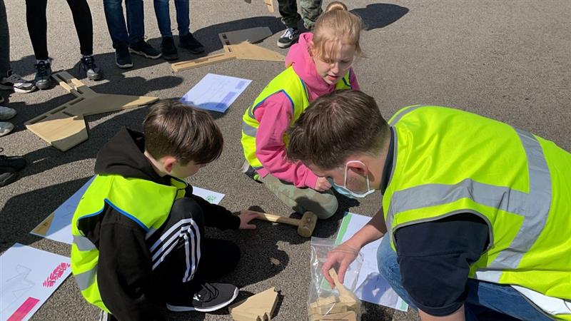 children work with a member of the team and build a bench