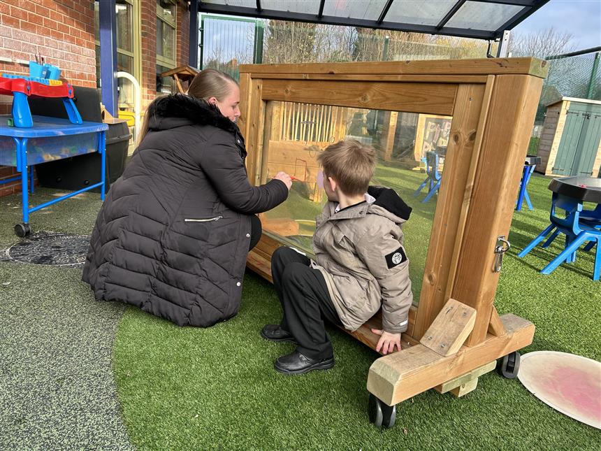 A teacher is sat with an SEN student as they draw on an Interactive Paint Panel on Wheels.