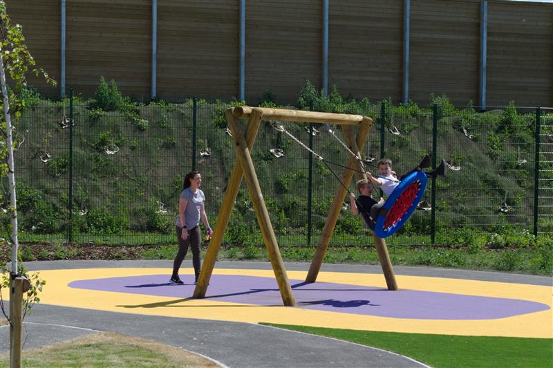 an adult pushes the basket swing back and forth with 2 children in it