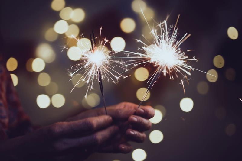 an adult holds 2 sparklers in their hand 