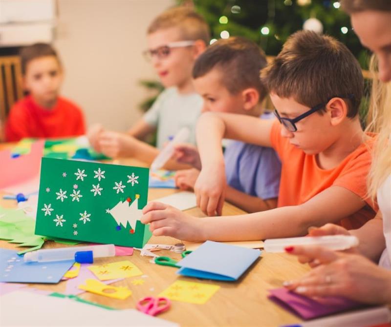 children sit and make christmas cards