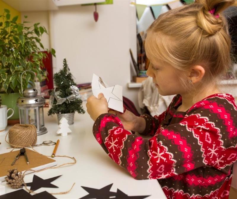a little girl sits and cuts on christmas cards