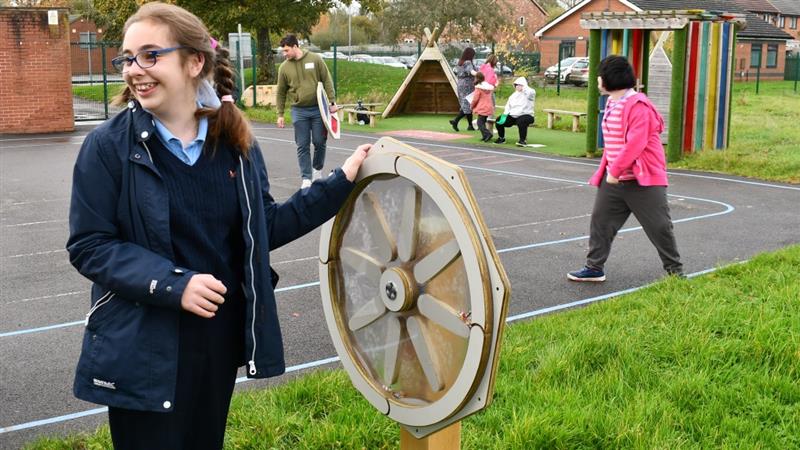 a young girl stands at the sound sensory spinner and spins it round