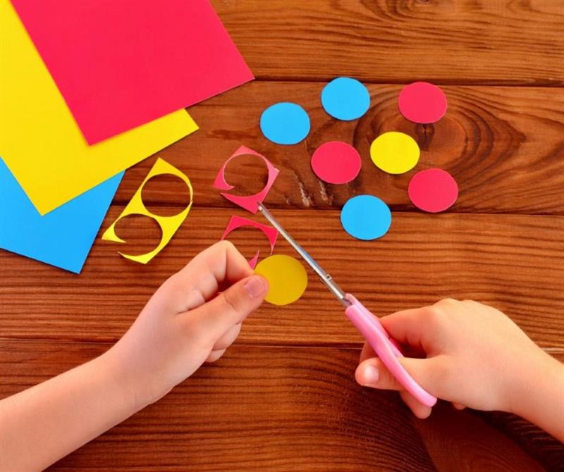 a child cutting out different coloured circles of paper