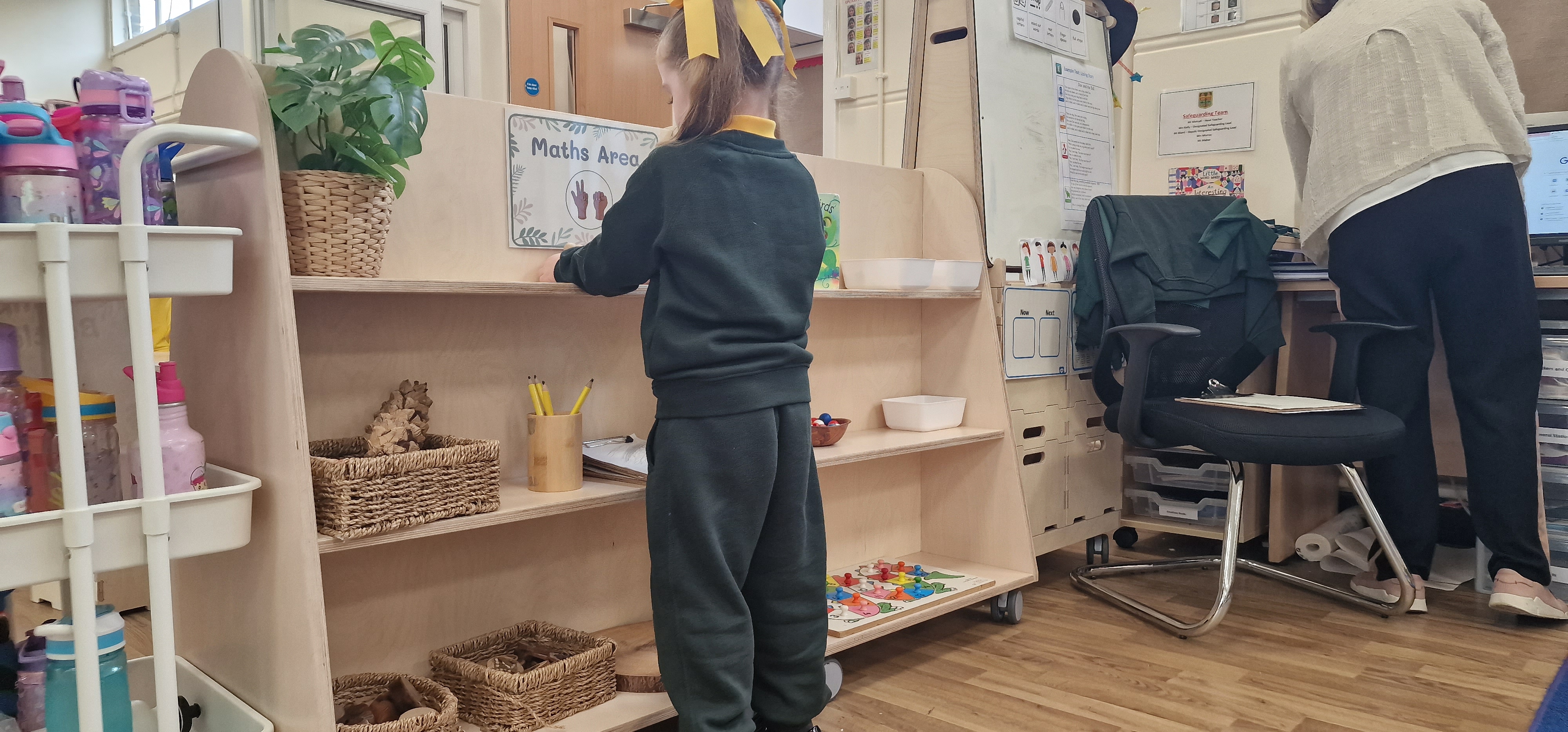 A little girl is looking through a mobile bookcase and is selecting a book to read.