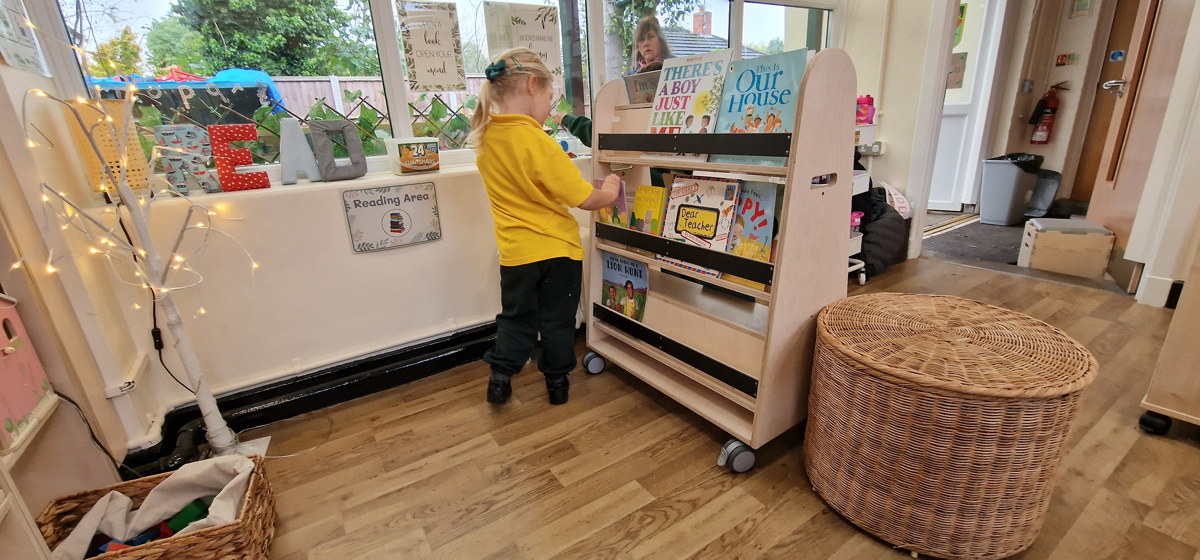 A little girl is browsing through a mobile bookcase as she selects a book.