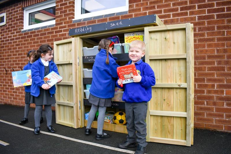 children retrieve books from the store and then stand in front of the cupboard and have their photo taken with them