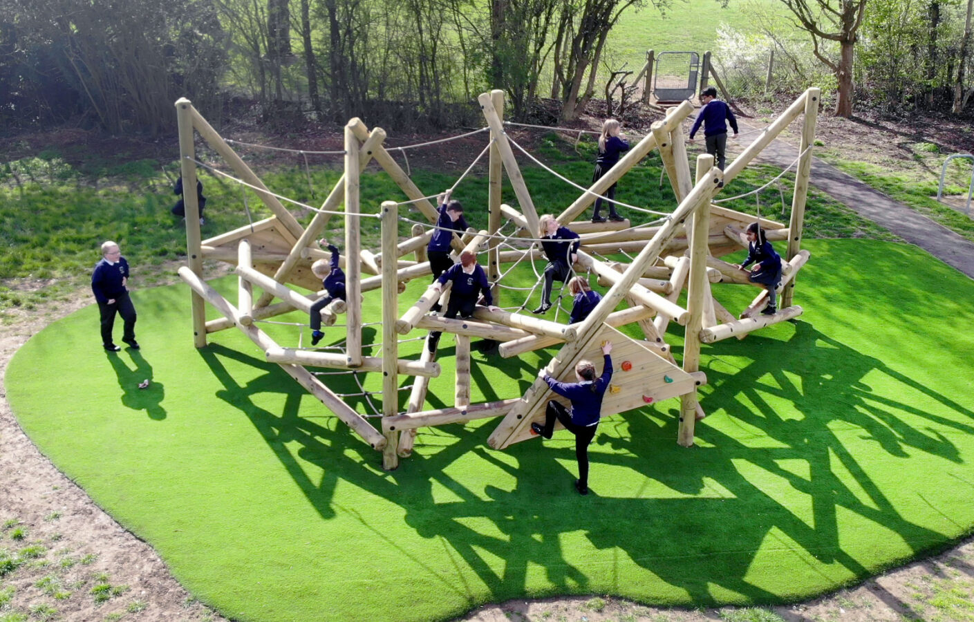 11 children playing on the Crinkle Crags Climber, a climbing frame produced by Pentagon Play.