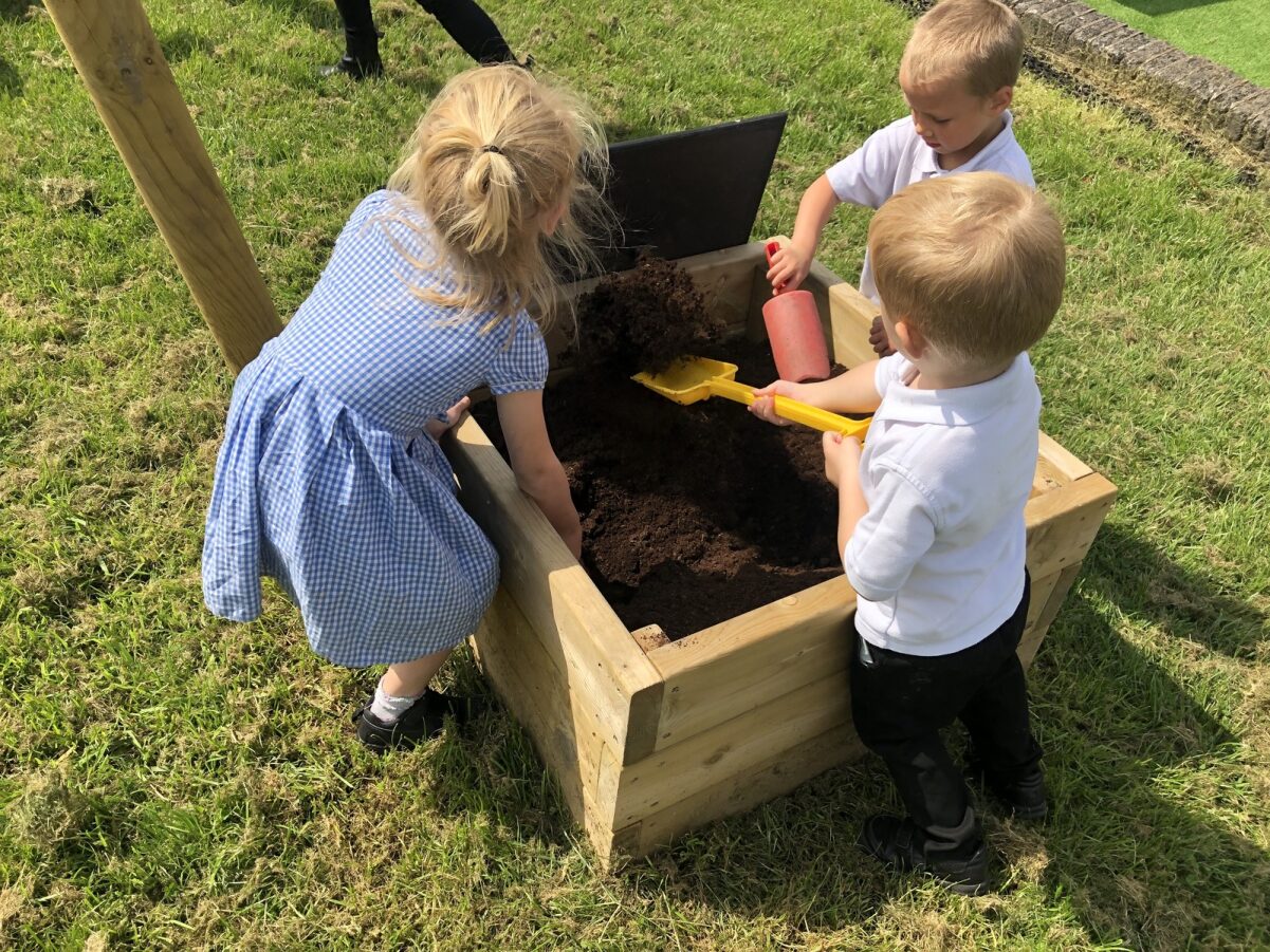 3 children playing with a mud box that Pentagon Play provided to St Mary's Roman Catholic Primary School