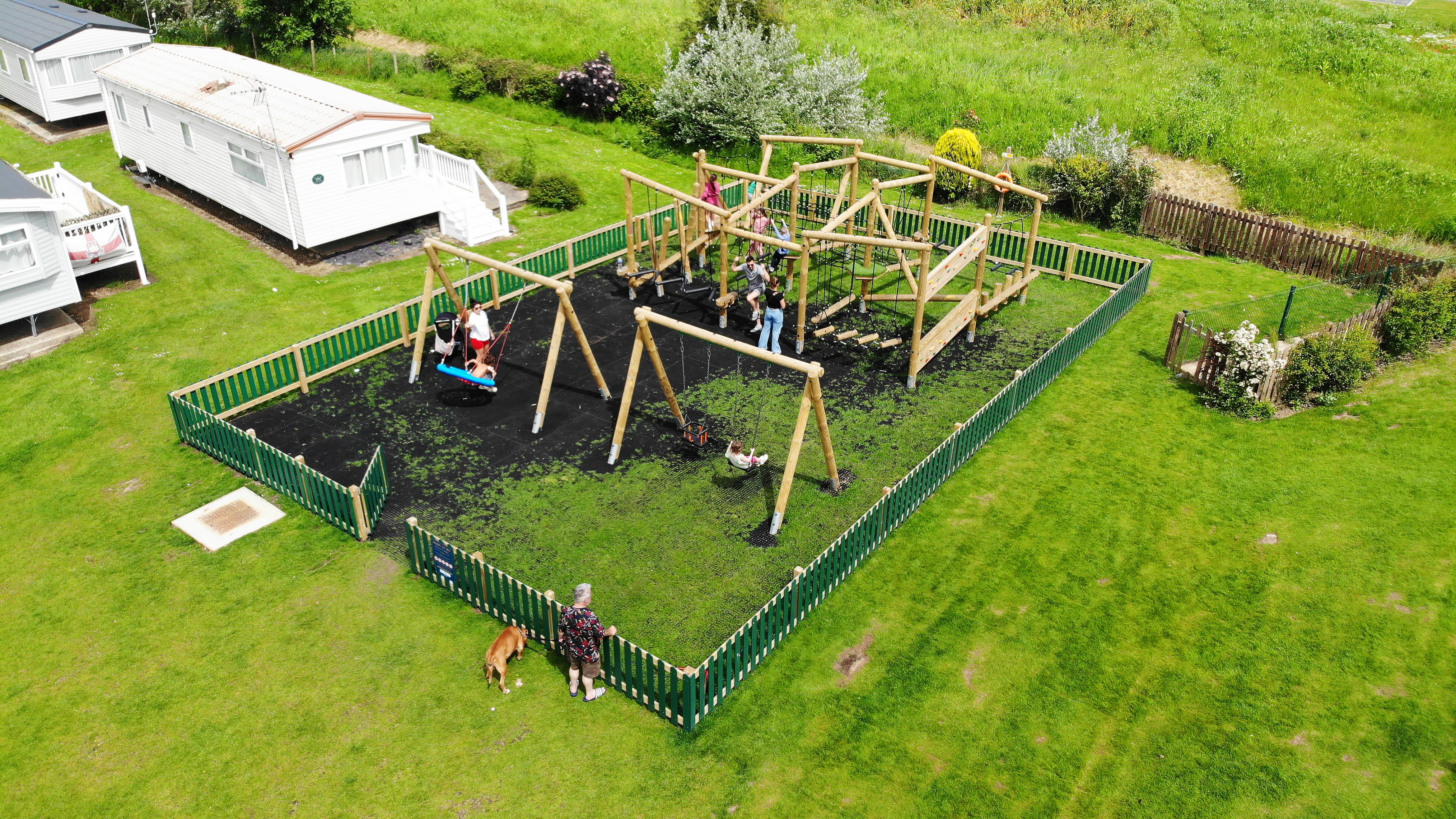 A photo showing the timber swings that have been installed on the Grizedale Forest Circuit playground. A group of children are playing with each piece of equipment.