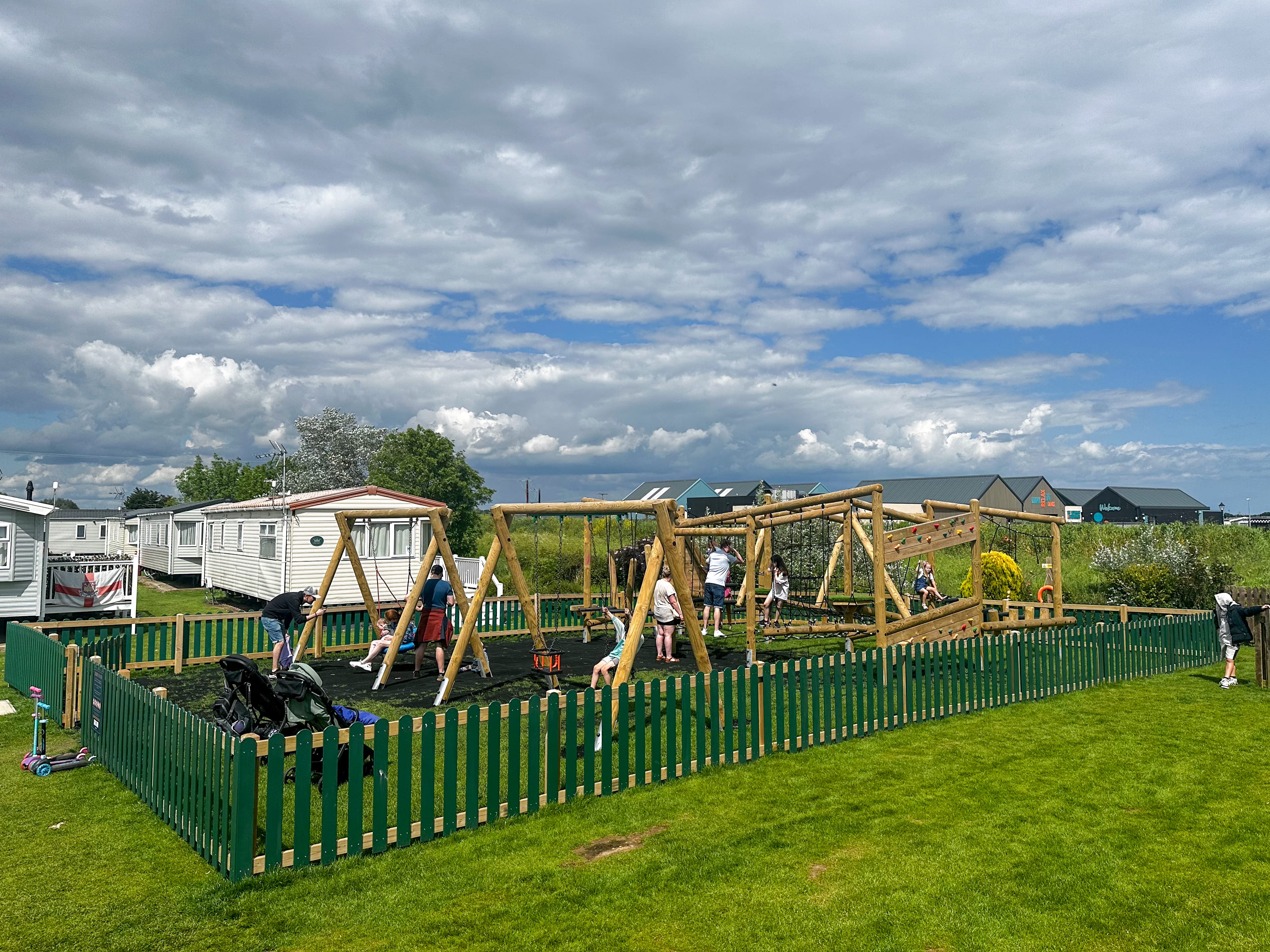 The Grizedale Forest Circuit playground is full of people playing on all the pieces of play equipment. The play area is surrounded by green HDPE Bow Top fencing.