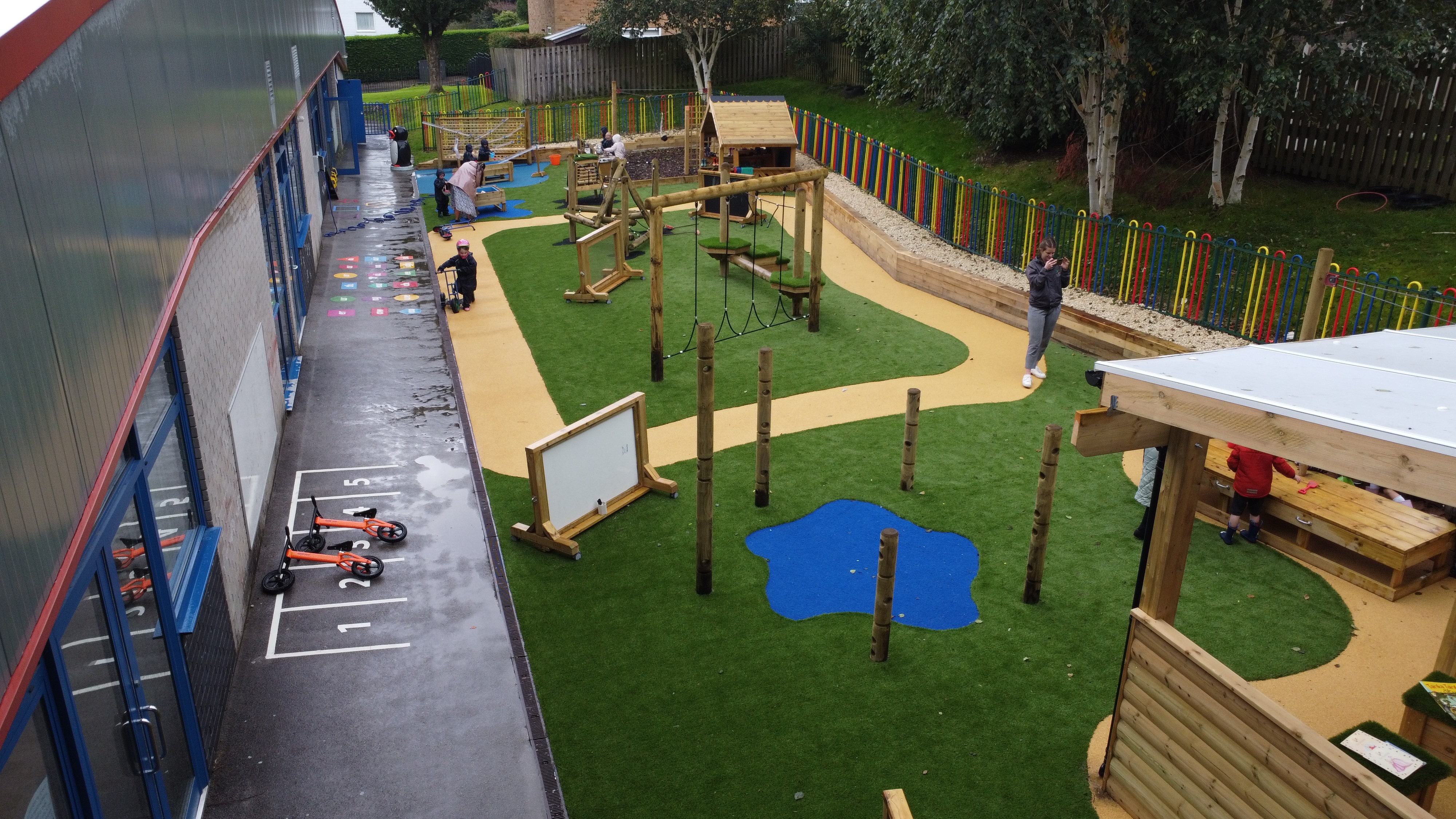 A birdseye photo showing the artificial grass that has been installed by Pentagon Play. Blue splatter patterns can be seen on the surface, which are custom artificial grass graphics.