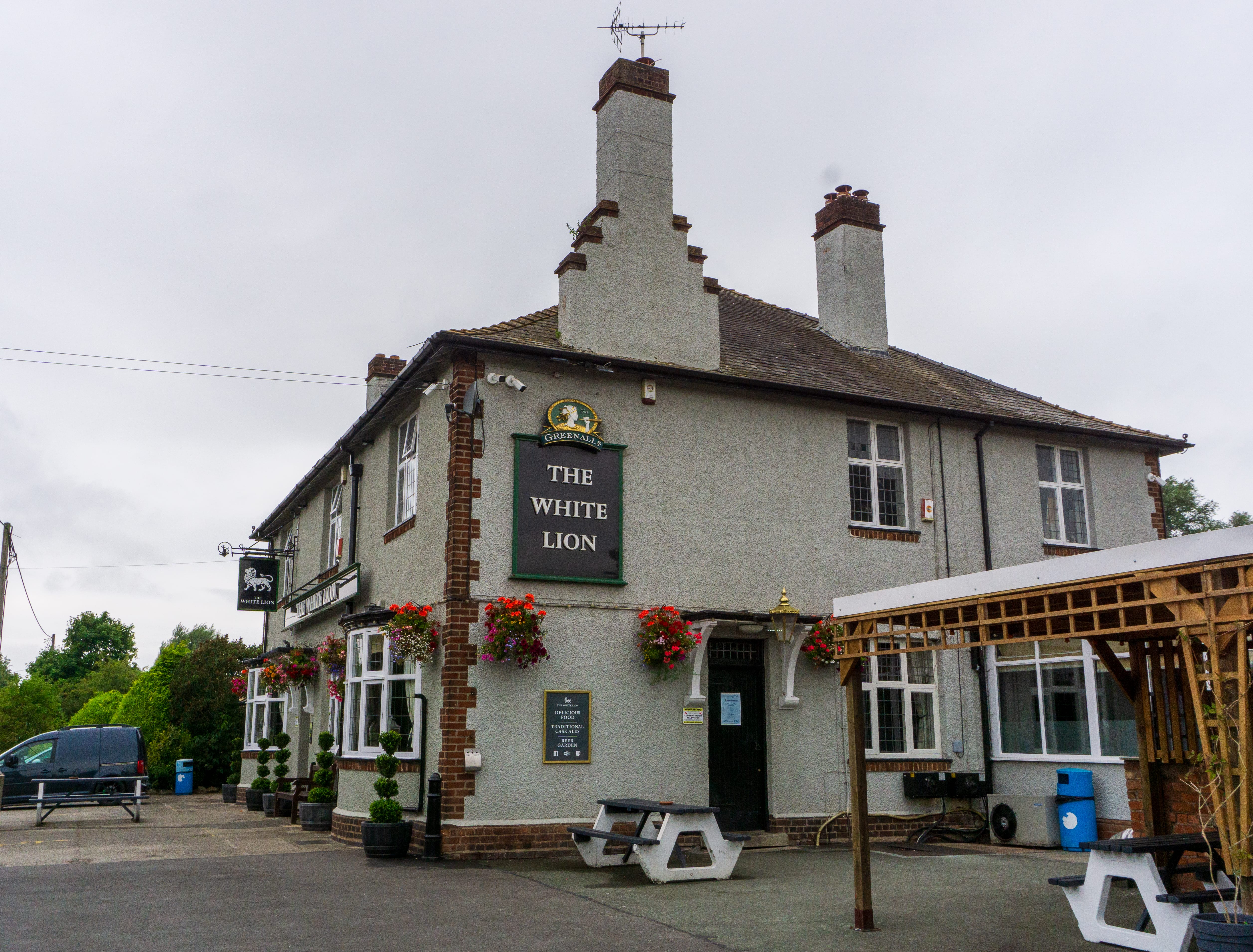 A picture of The White Lion pub from outside. It's a grey house with brown brick work around the edges