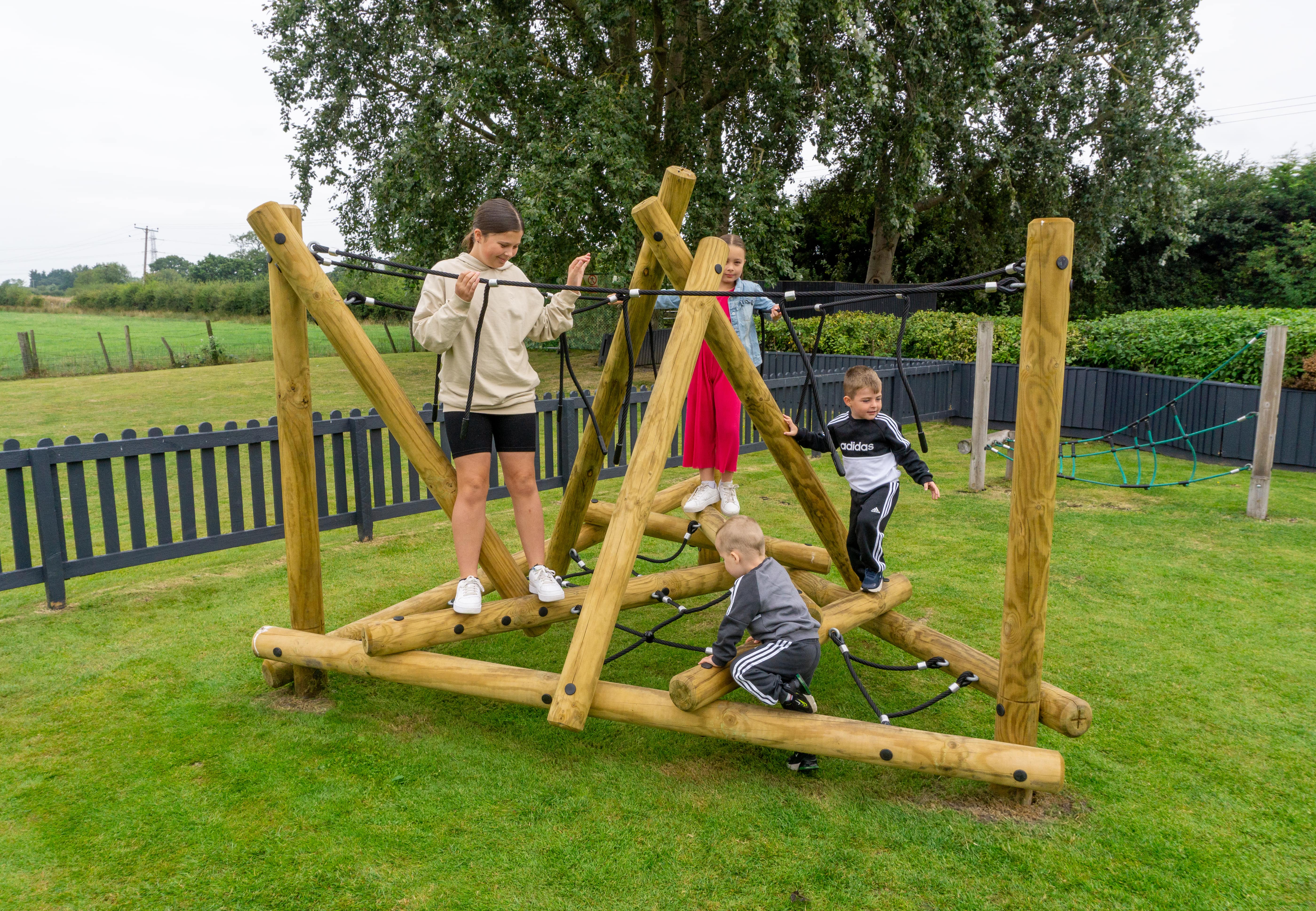 A Mam Tor Mountain Climber that was installed on a grass surface. A group of children are playing on the equipment.