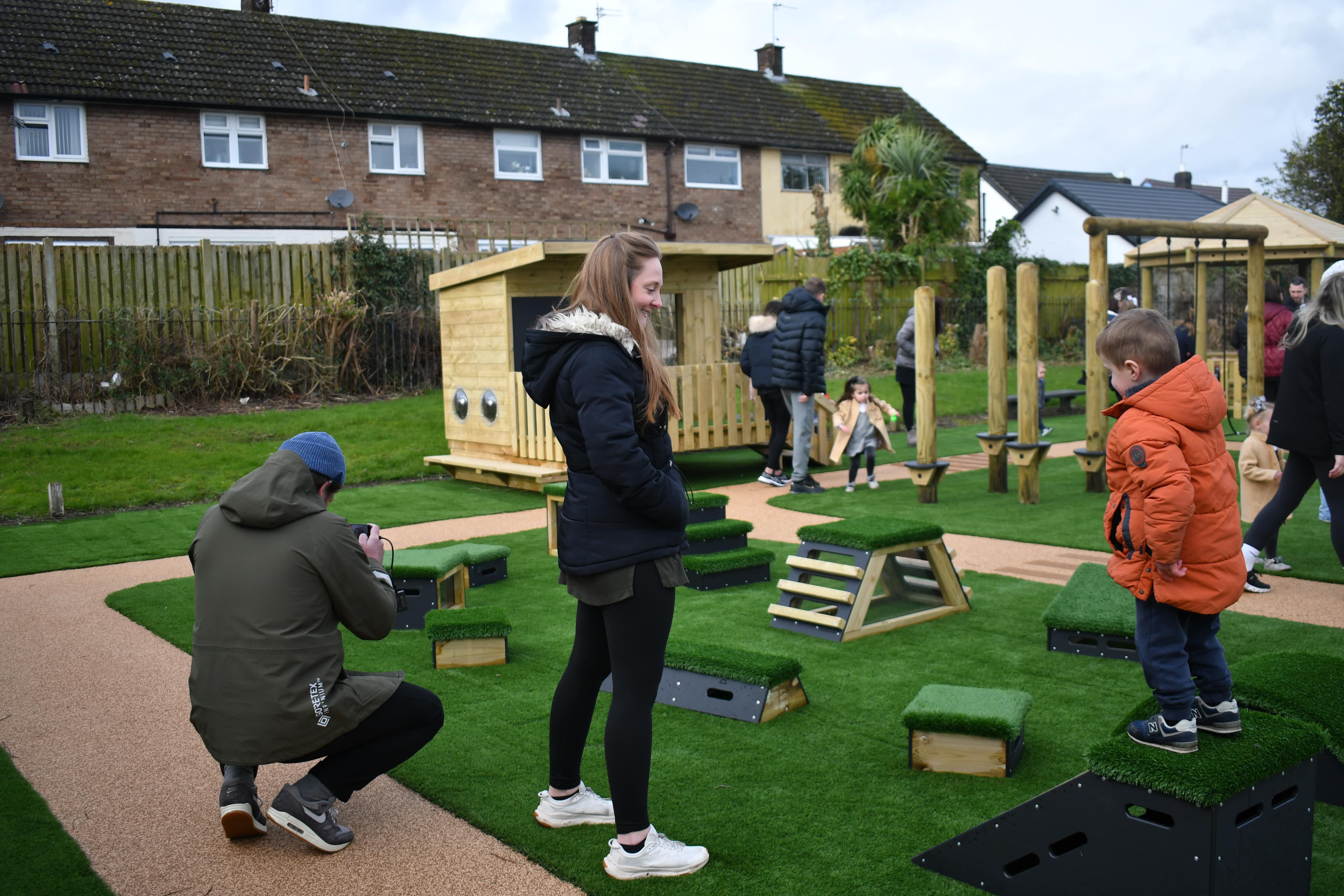 A group of different aged people are surrounding the Get Set, Go! Blocks and are laughing and smiling.