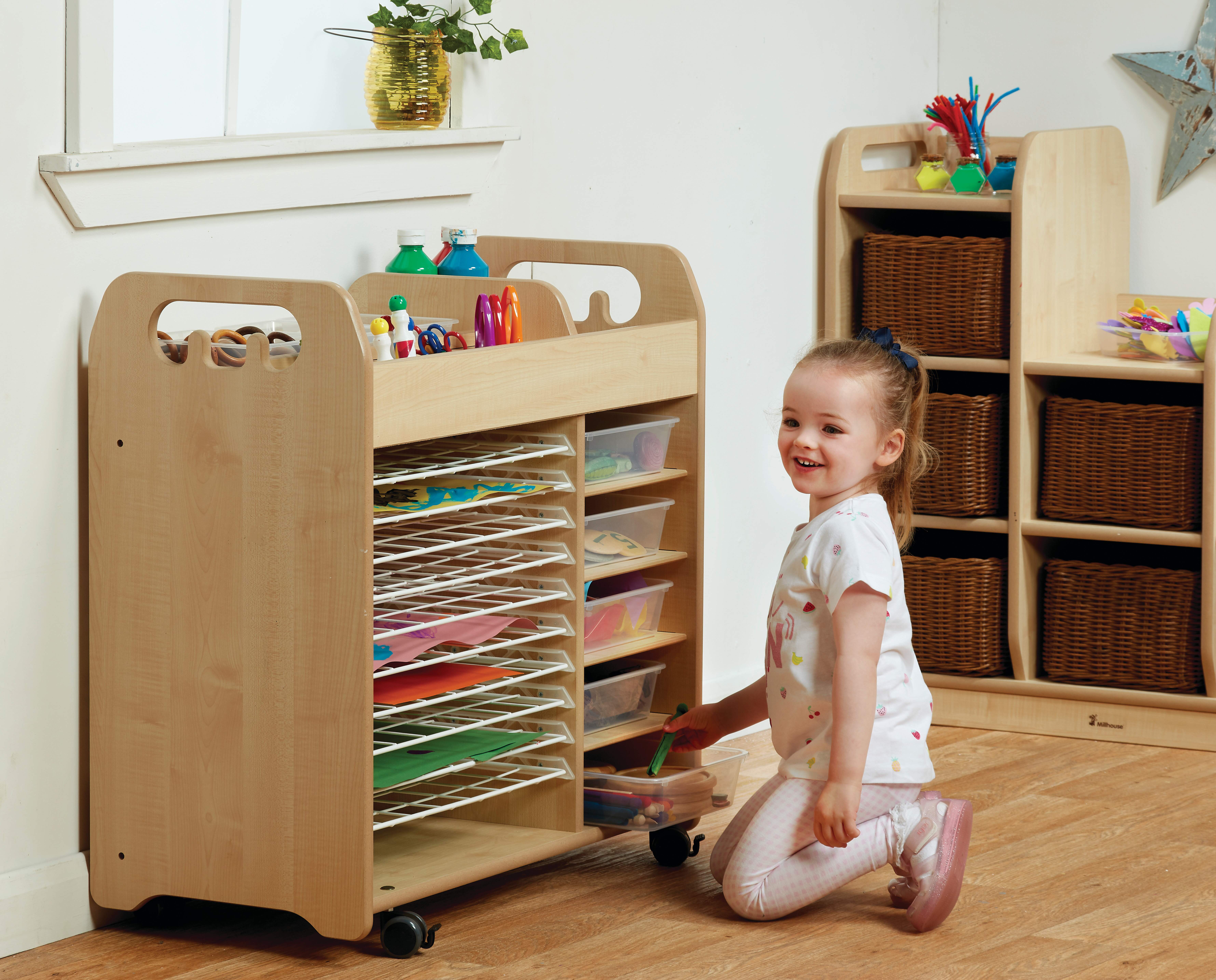 A little girl is going through a tray storage unit as she smiles at the camera. Each tray holds different resources in them, making it a perfect arts and crafts provision.