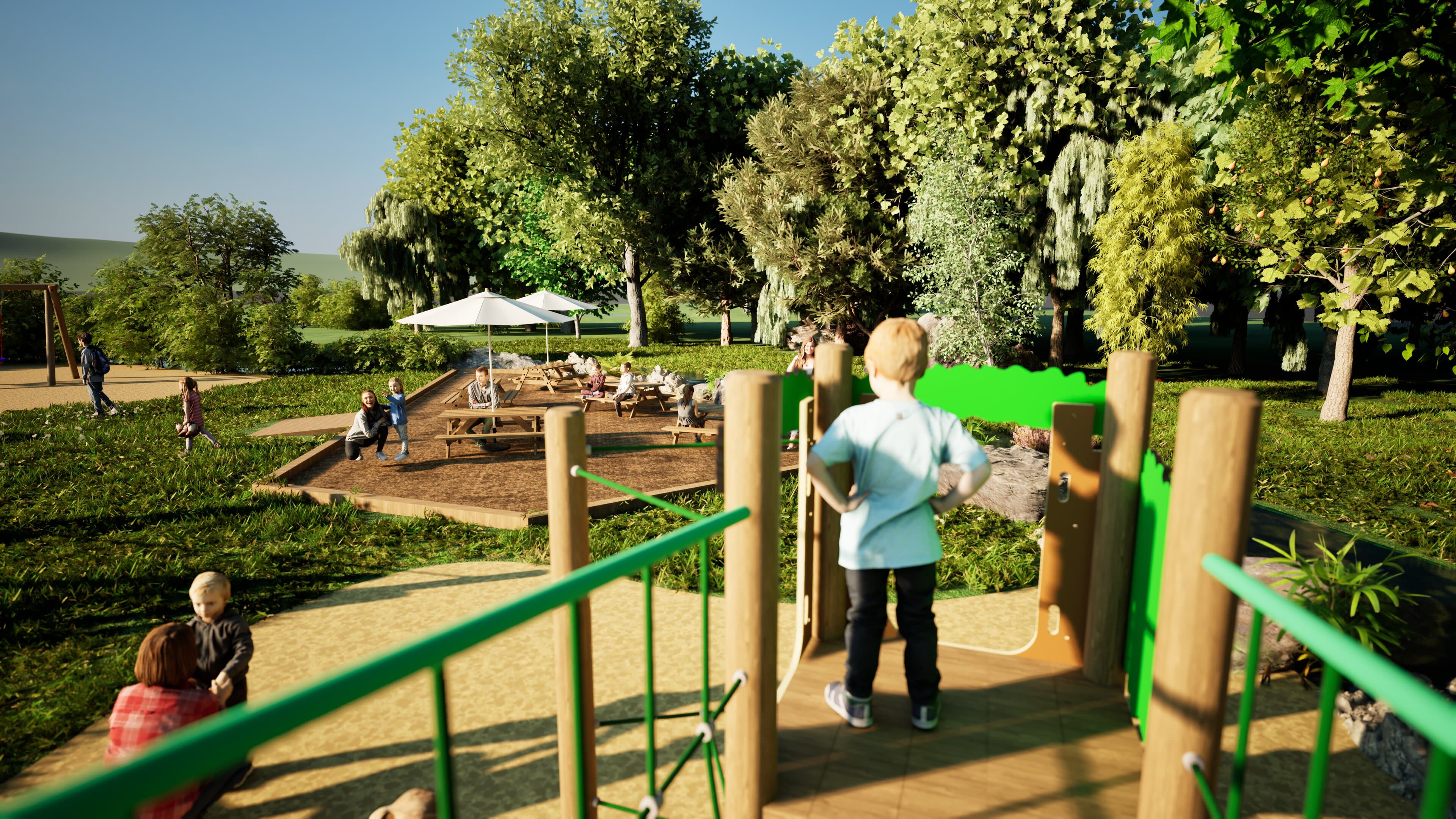 A child is stood on the platform that is a part of the Hawk Play Tower. The child is overlooking a seating area, with a group of people sat on the picnic benches and talking with each other.