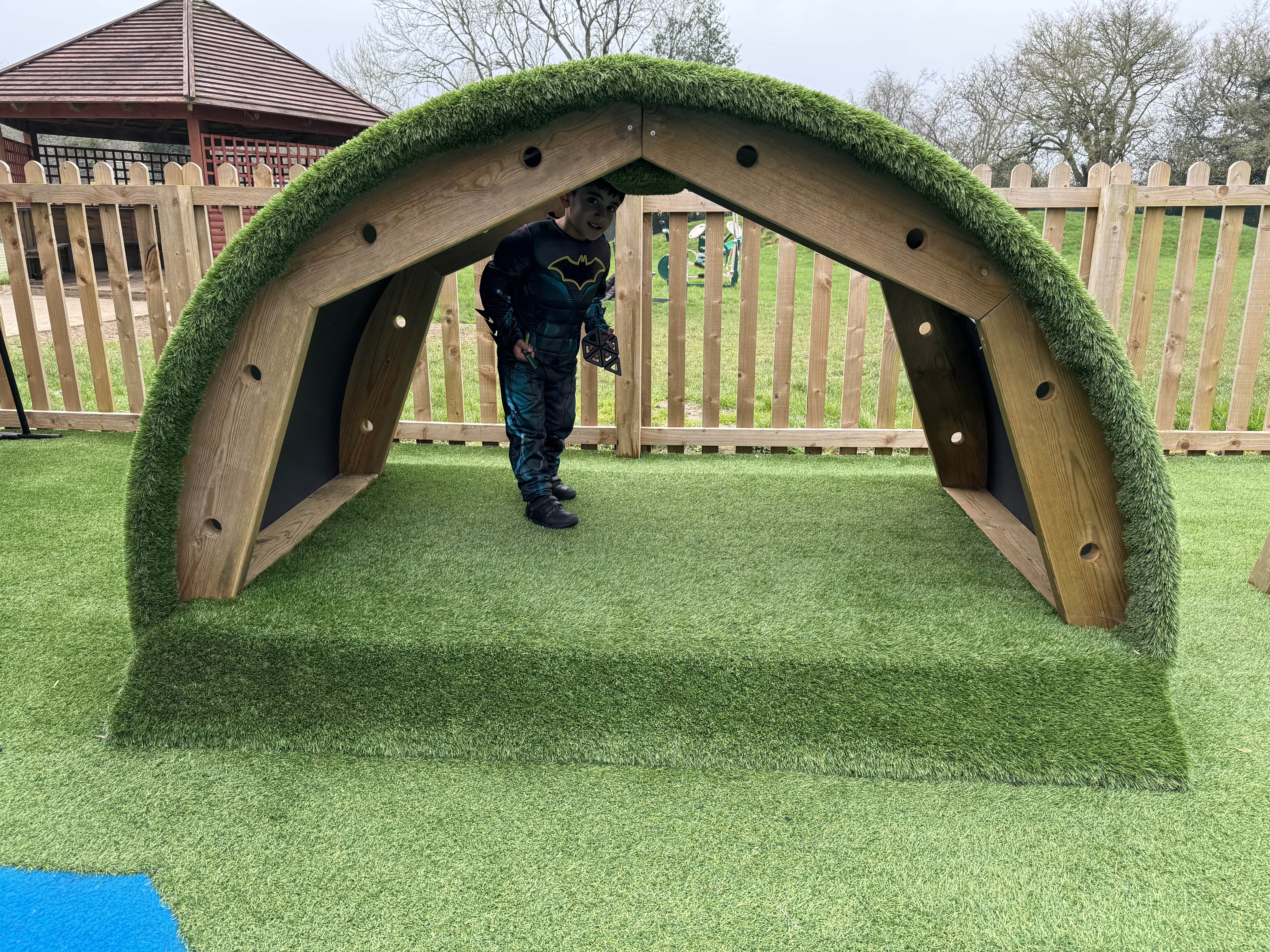 A clear view of the Hill Den, with a child being seen on the inside. The child is looking at the camera and is smiling.