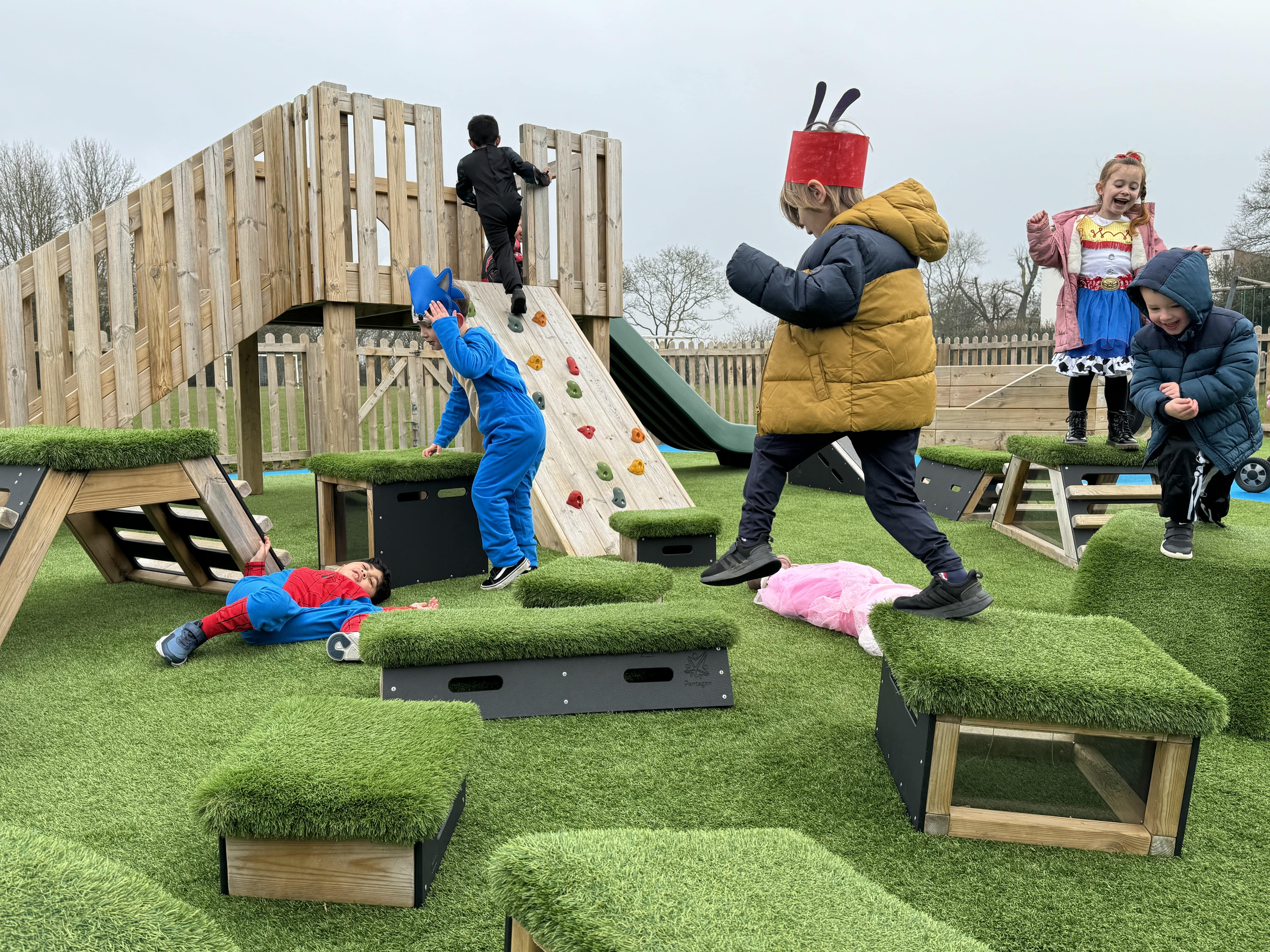 A huge group of children are all playing with the Get Set, Go! Blocks and have made an obstacle course. One child is climbing the play tower by the climbing wall.