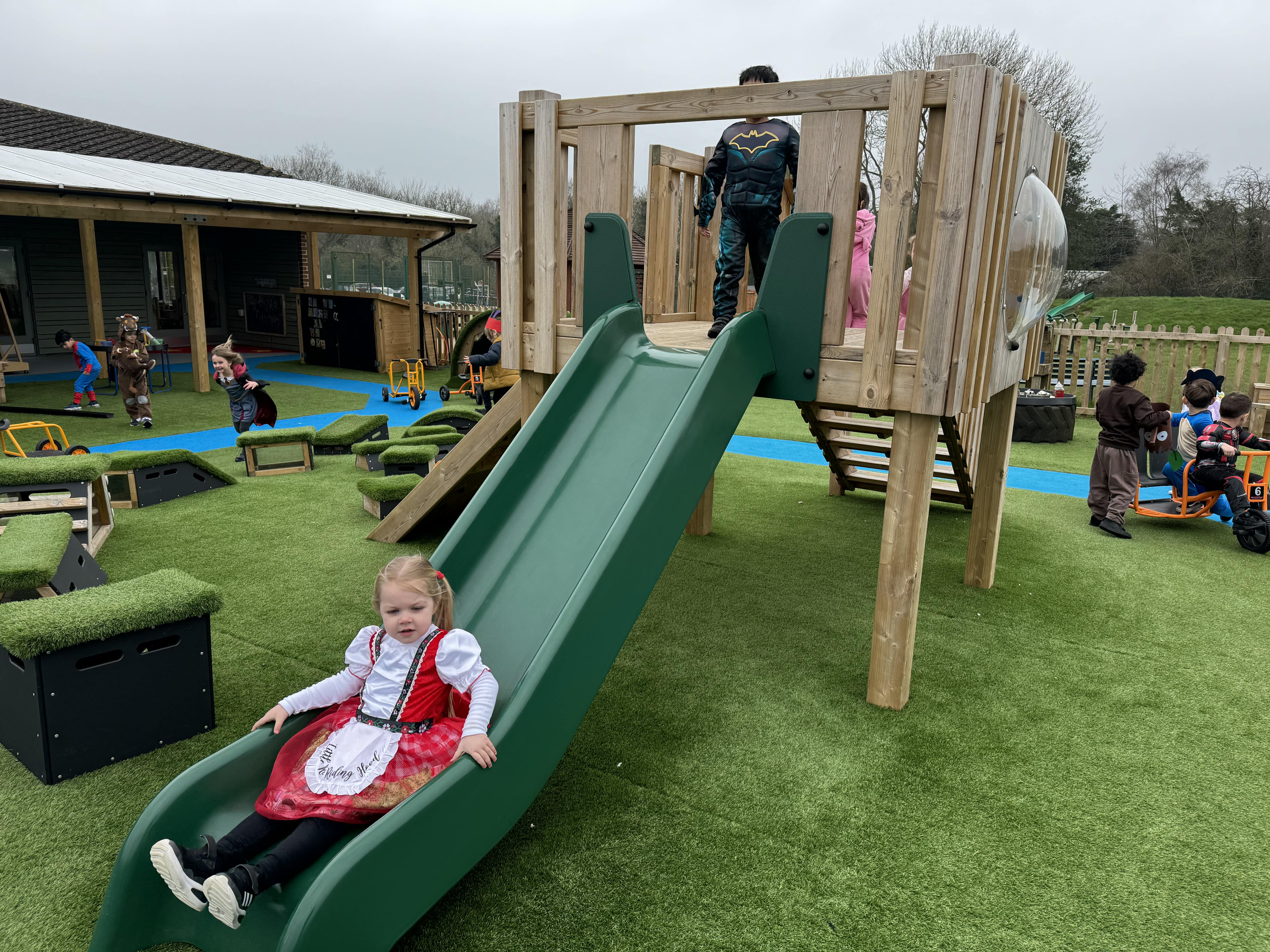 Children are playing on a modular Play Tower that has been installed on artificial grass.