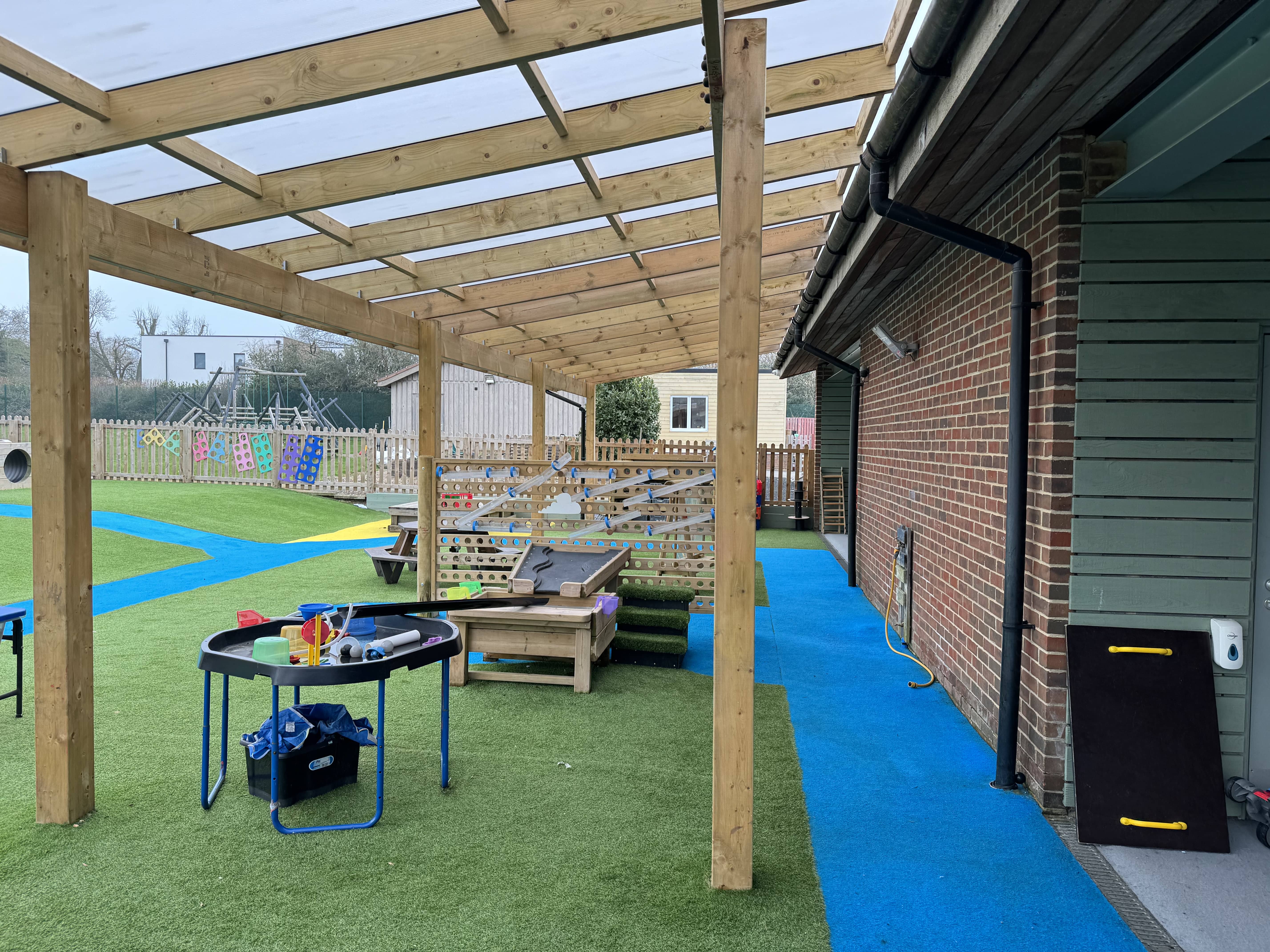 The underneath of a school canopy, with a variety of play equipment stored underneath it.