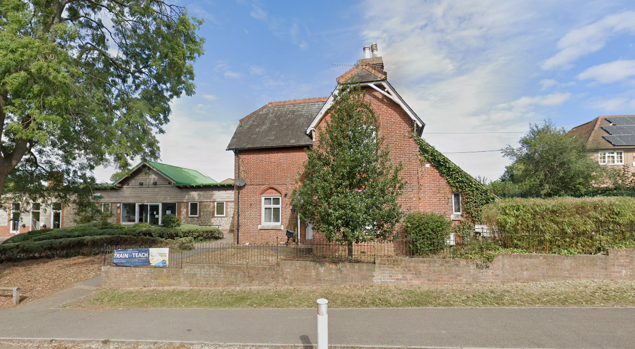 A school building that is located next to a road and has a building attached to the side of it.